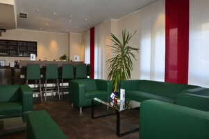 A reception area with green seating, a reception desk, and a bar area in the background.