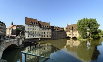 A historic European town with a river, stone bridges, and traditional buildings.
