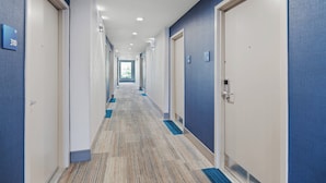 A hotel corridor with doors numbered 310 and 311, carpeted floors, and a blue wall. - Holiday Inn Express Sunnyvale - Silicon Valley by IHG (Sunnyvale)