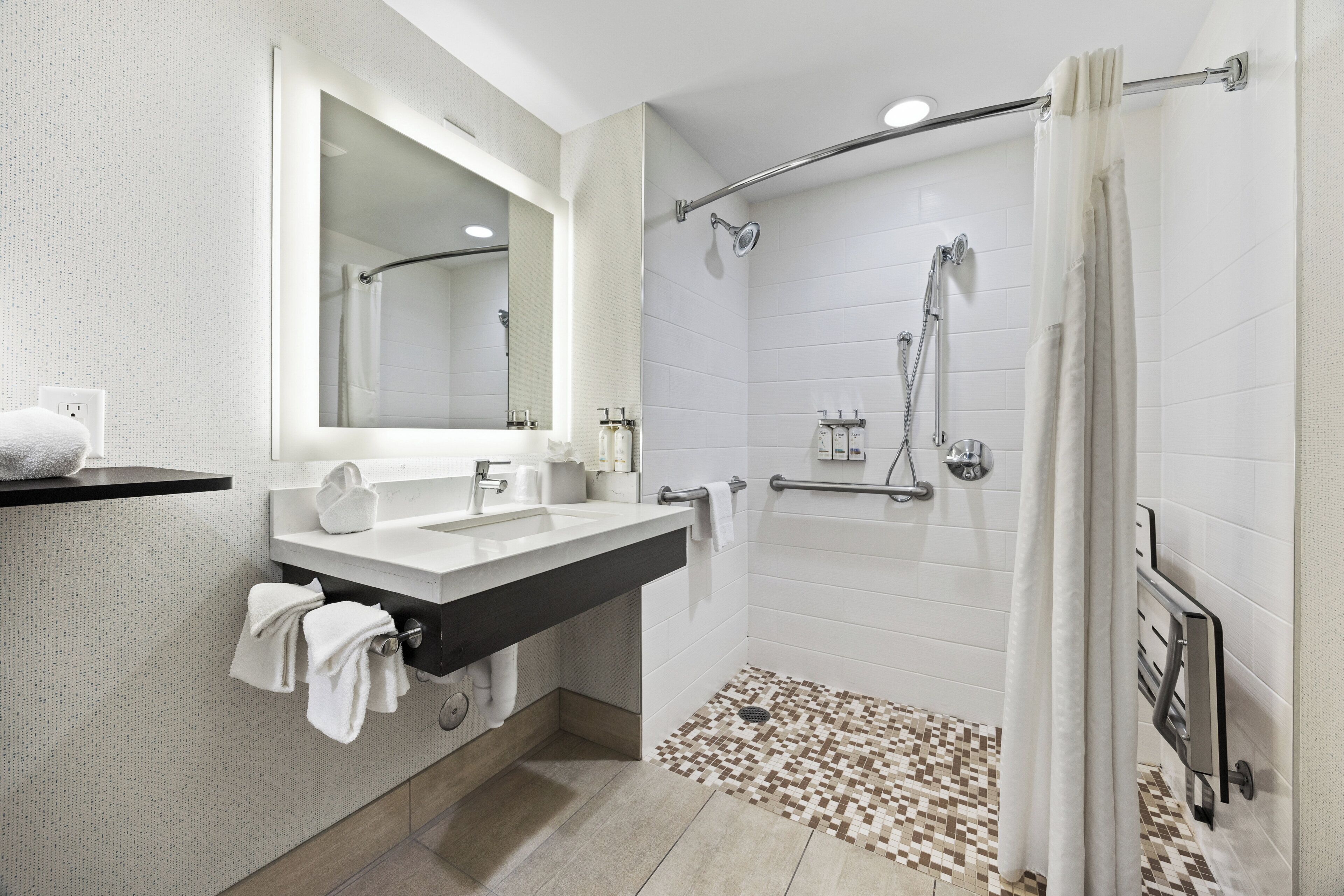 A modern bathroom with a large mirror, two sinks, a shower with a glass door, and a patterned floor.