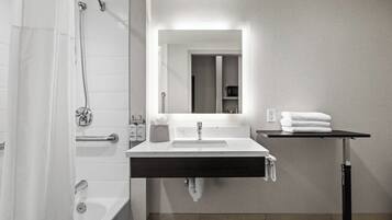 A modern bathroom with a bathtub, a sink with a mirror, and a towel rack.