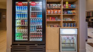 Ein Getränkeautomat mit einer Auswahl an Getränken und Snacks, darunter Coca-Cola, Lay's und Hershey's.