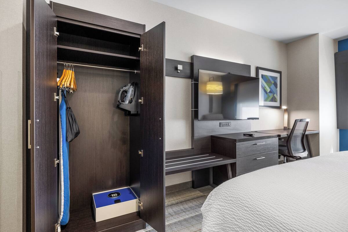 Une chambre d’hôtel équipée d’un placard, d’un bureau avec une chaise, d’un lit et d’une télévision.