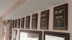 Una pared con varios cuadros de premios y placas conmemorativas, incluyendo una con la etiqueta 'Approved Diamond Rated 2007'.