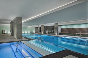 Piscina interior moderna com pistas demarcadas, área de vestiários e balcão de recepção.