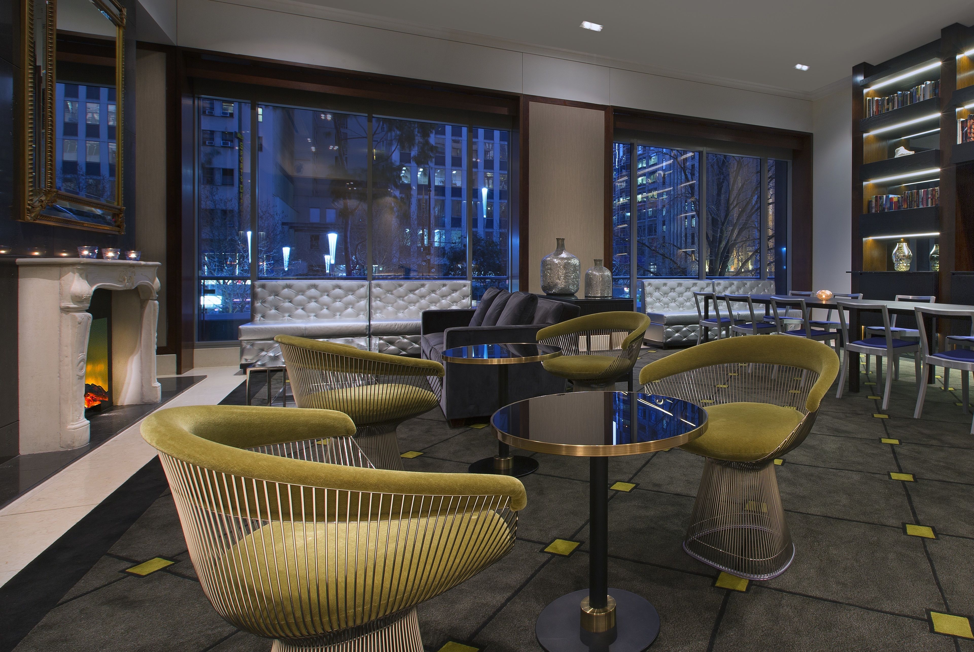 A modern lounge area with comfortable seating, a fireplace, and large windows offering city views.