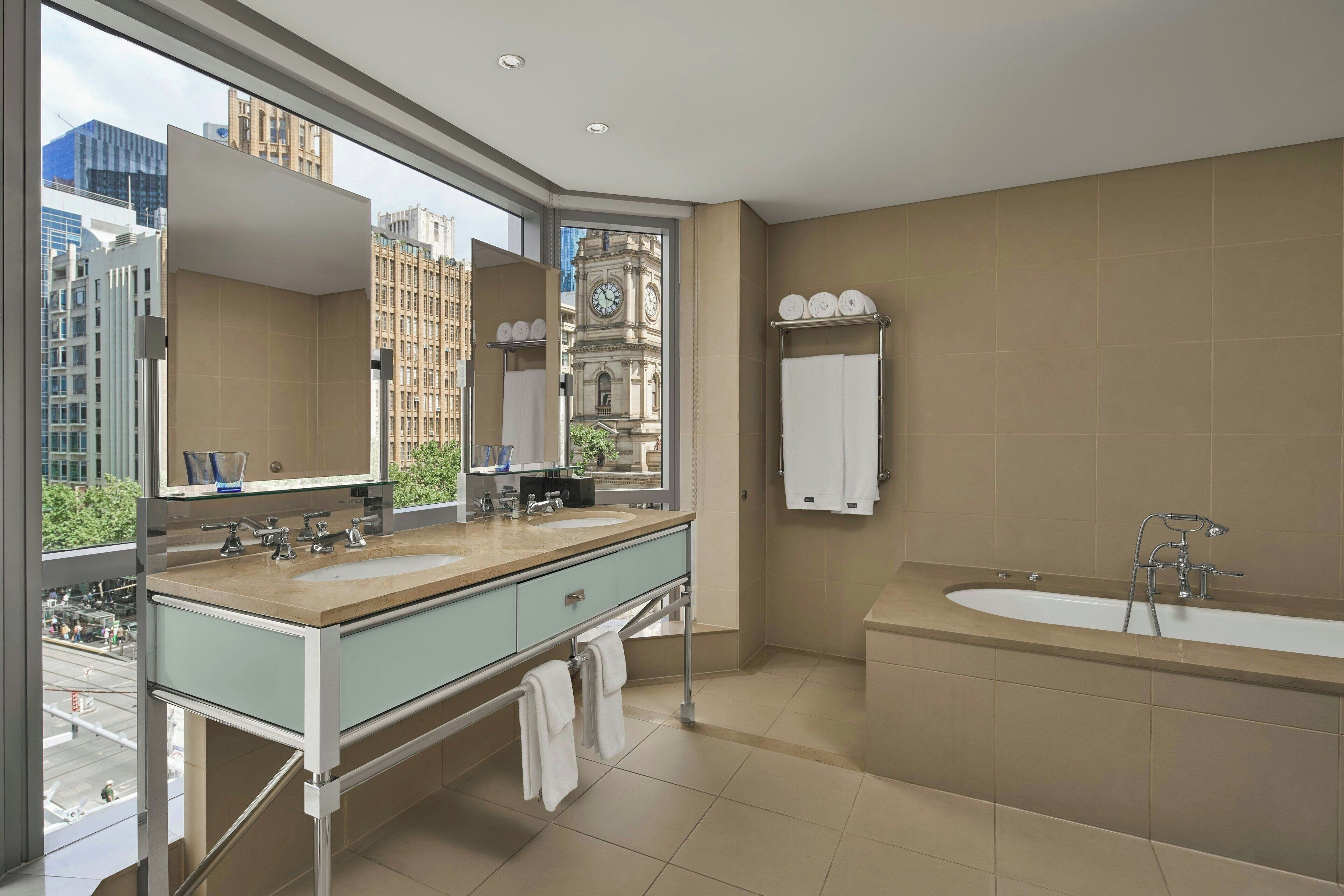 Un baño moderno con un ventanal amplio, una bañera e un lavabo doble con espejo.
