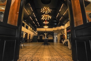 Un hall d’entrée spacieux, doté d’un sol à motifs, d’un lustre central et d’un escalier menant aux étages supérieurs.