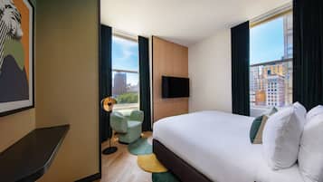 A hotel room with a large bed, a flat-screen TV, a desk, and a chair.