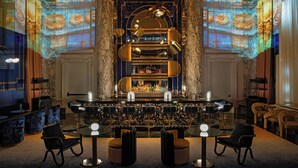 A bar area with a bar counter, multiple stools, and a projection of floral patterns on the walls. - W New York - Union Square (New York)