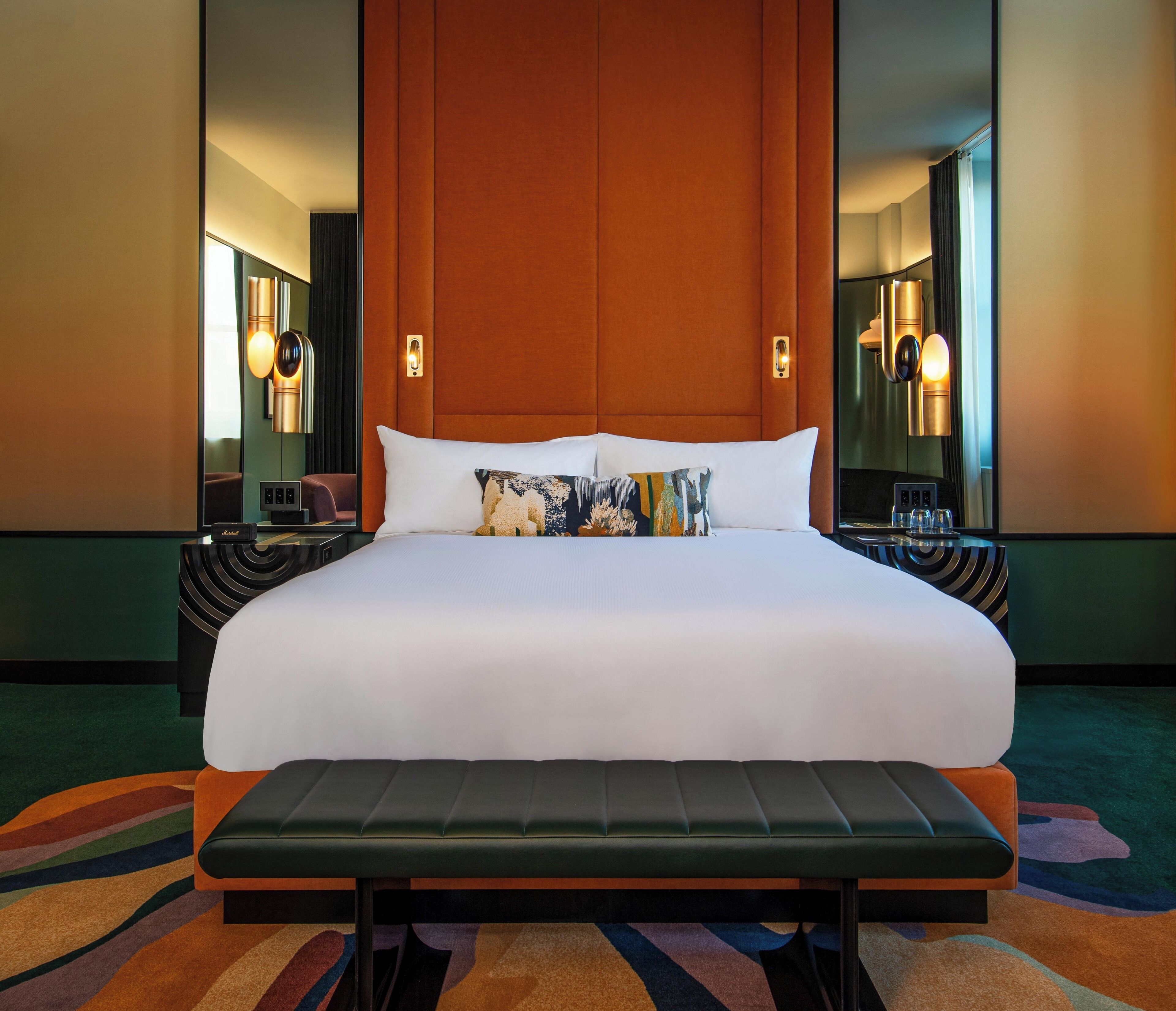 A large bed with a wooden headboard, two bedside tables, and a bench at the foot of the bed.
