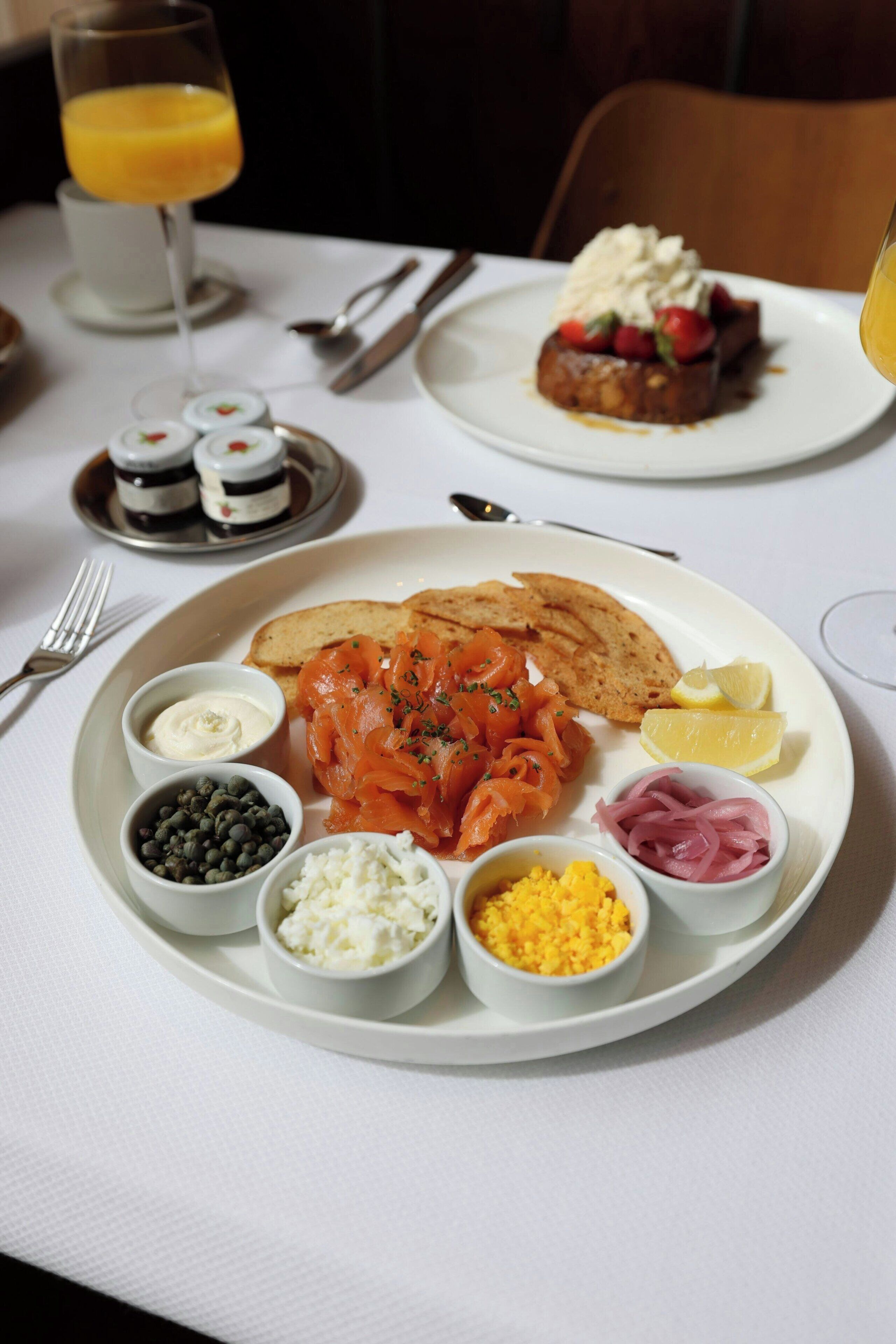 Desayuno con platos de comida, incluyendo salmón ahumado, huevos y diferentes acompañamientos.