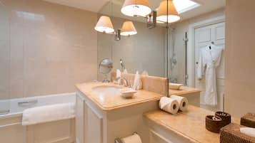 Ein modernes Badezimmer mit Badewanne, Waschbecken und Spiegel. Handtücher und Pflegeprodukte sind sichtbar.