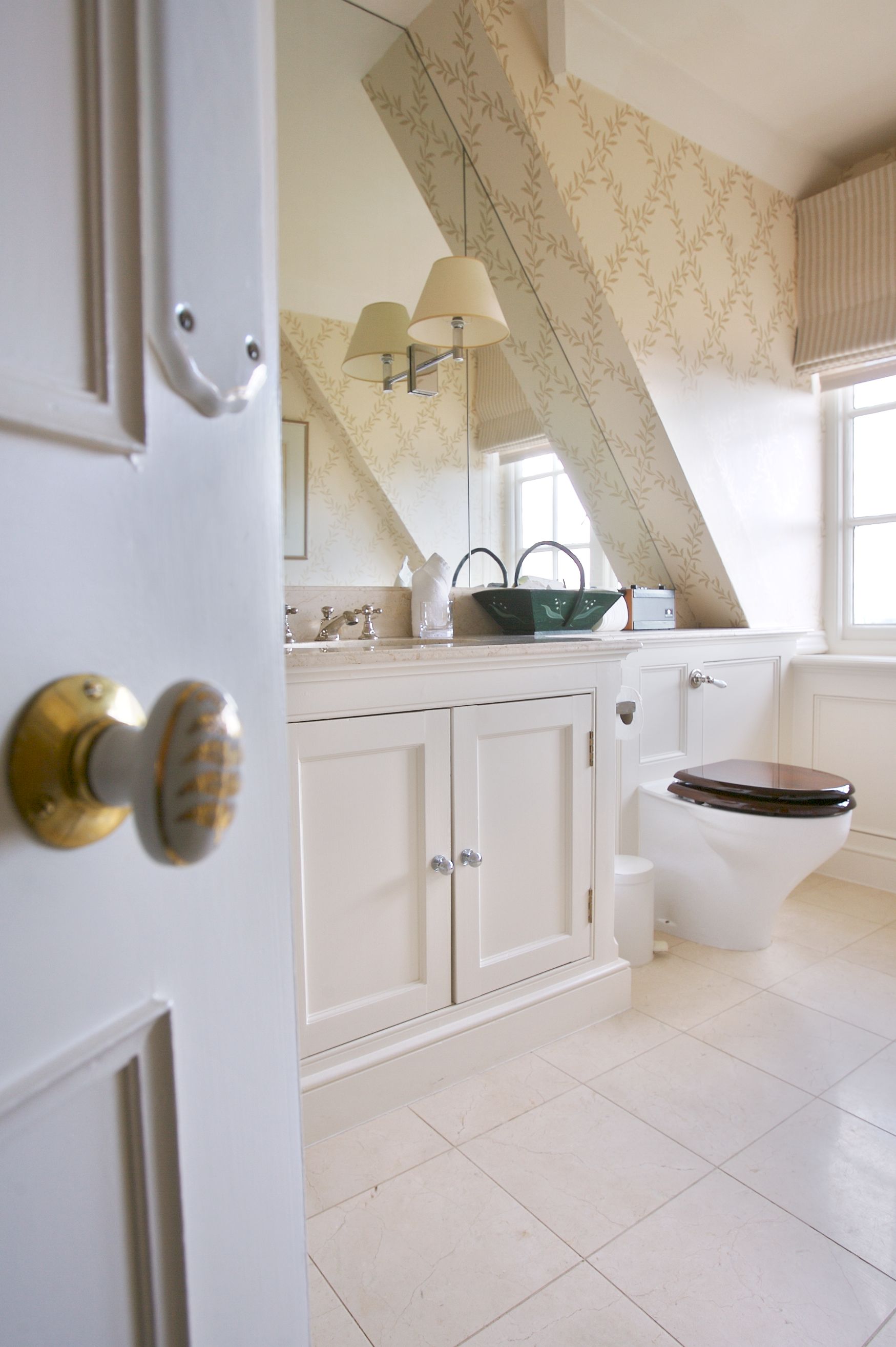 A bathroom with a white door, a toilet, a sink with a mirror, and a window with a view of the outside.