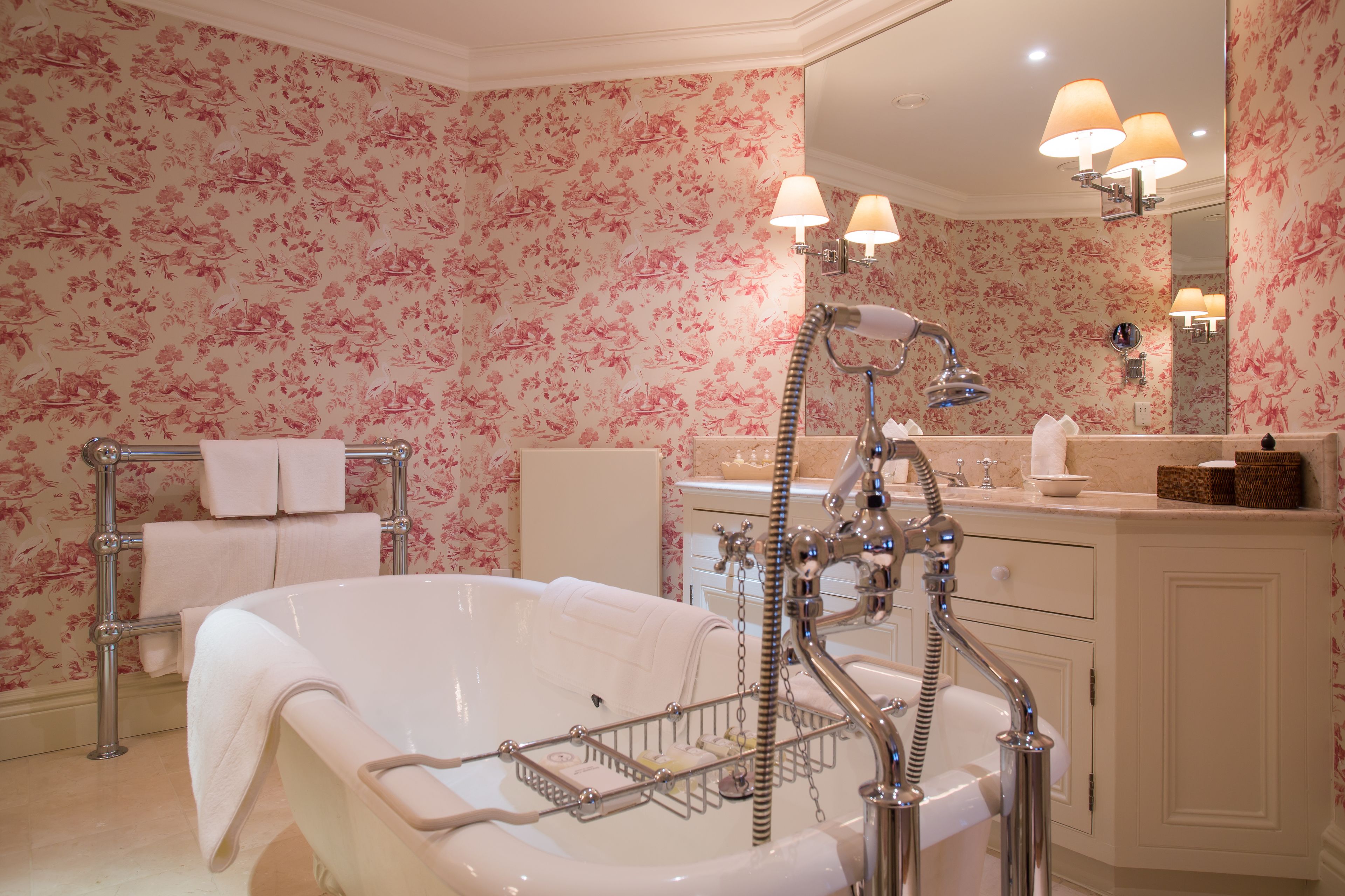 A bathroom with a freestanding bathtub, a vanity with a mirror, and a towel rack.