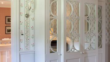 Ein Zimmer mit einem weißen Wandschrank mit dekorativen Glasfeldern und floralem Wandpapier.