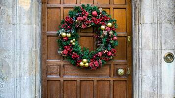 A wooden door with a festive wreath and a stone archway.
