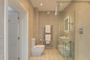 A modern bathroom with a toilet, sink, and glass-enclosed shower. - Farlam Hall Hotel & Restaurant (Brampton)