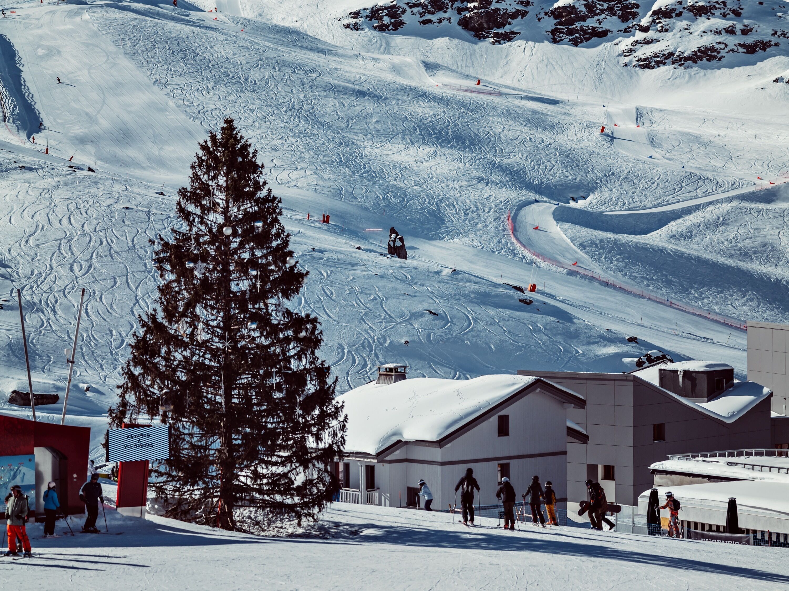 Une station de ski comprenant un bâtiment, un télésiège et un paysage enneigé.