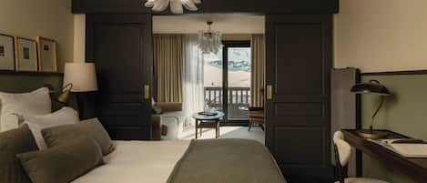 Habitación de hotel con cama, escritorio, silla, lámpara, mesa y vistas a un paisaje nevado.
