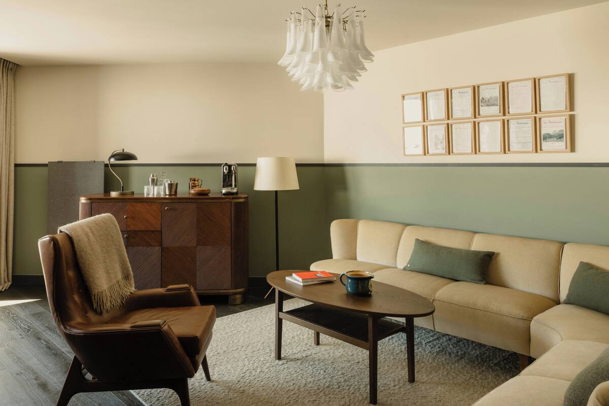 A modern living room with a sofa, a coffee table, a chair, a cabinet, and a chandelier.