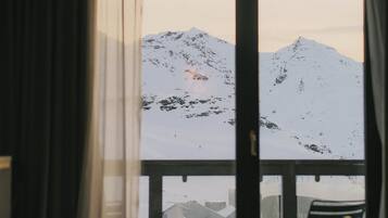 Une pièce avec vue sur des montagnes enneigées, visible à travers une grande fenêtre.