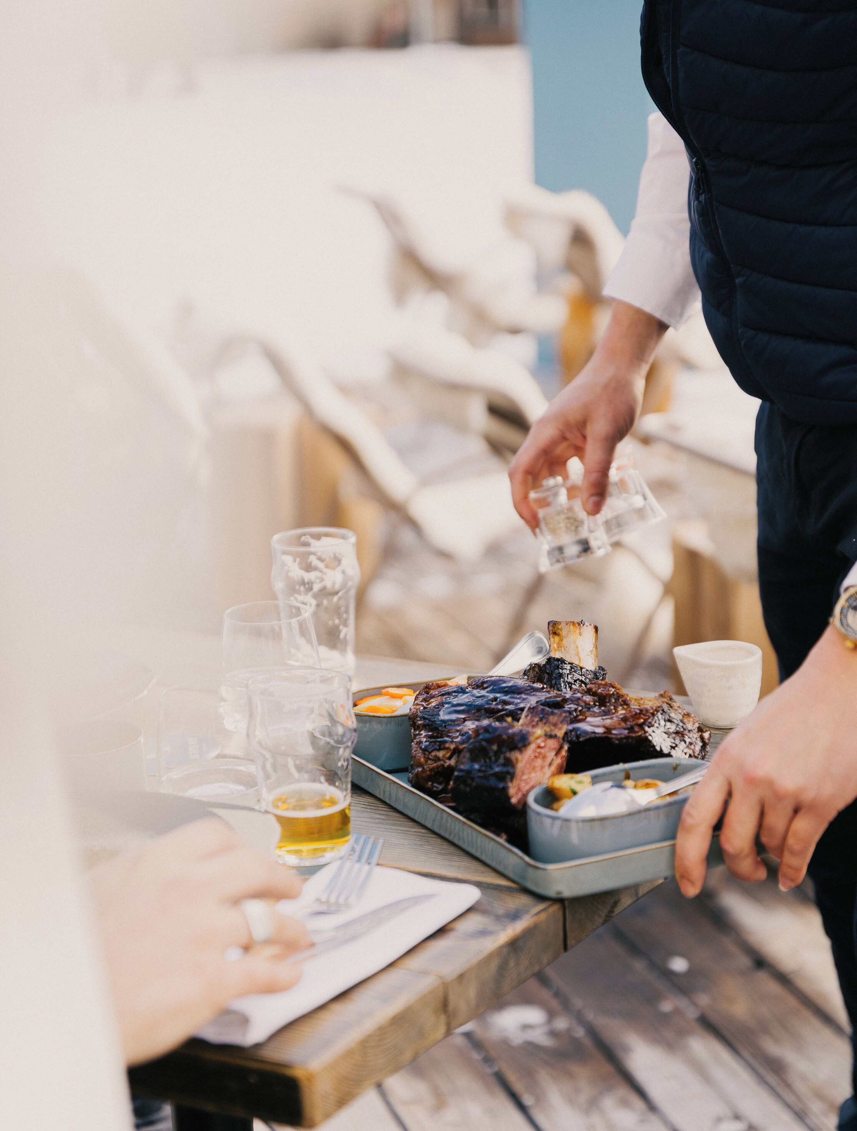 A dining table with a roasted meat dish, glasses, and a cup.