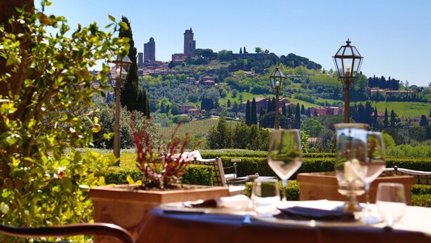 Une table dressée pour le dîner, avec vue sur une ville perchée sur une colline.