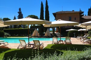 Una piscina al aire libre de temporada, sombrillas