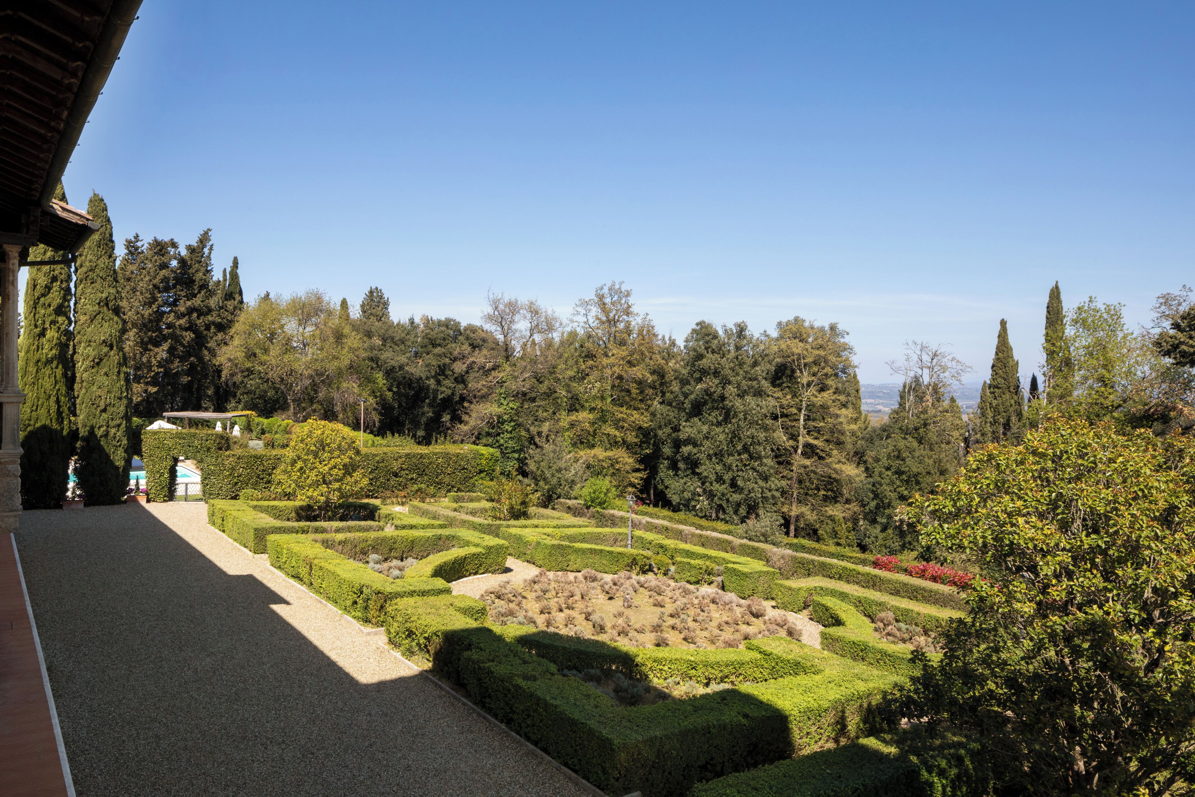 Un jardin aménagé avec des haies soigneusement taillées et une variété d’arbres.