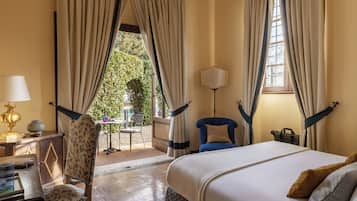 Ein Hotelzimmer mit Bett, Sessel, Lampe und Blick ins Freie.