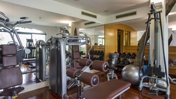 A gym with various exercise equipment, including weight machines, dumbbells, and a large exercise ball.