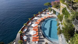 A poolside area with lounge chairs and umbrellas, overlooking a body of water. - Il San Pietro di Positano (Positano)