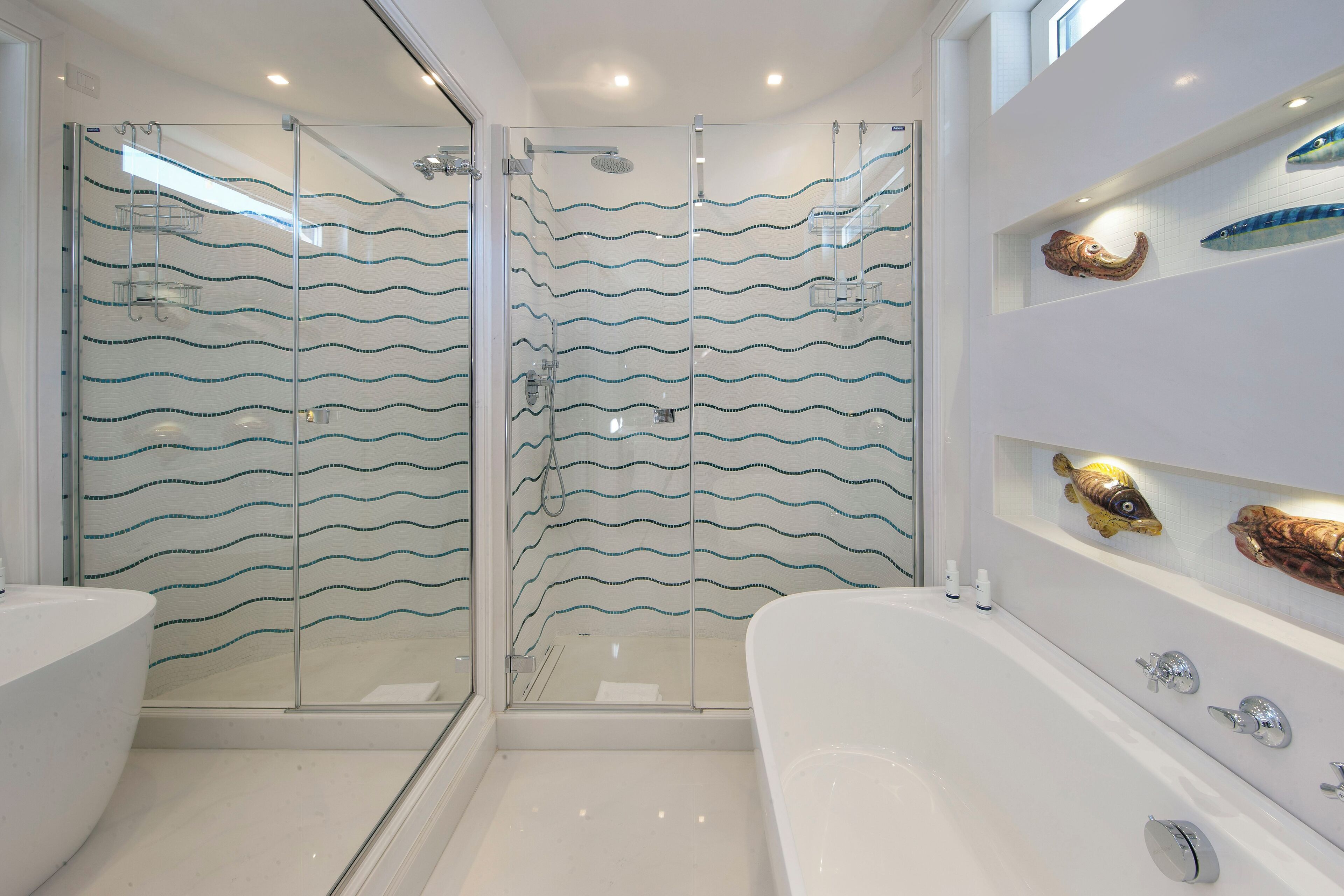 A modern bathroom with a glass-enclosed shower, a white bathtub, and decorative fish on the wall.