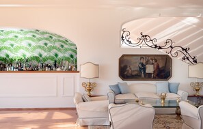 A well-furnished living room with a sofa set, a glass coffee table, and decorative lamps.