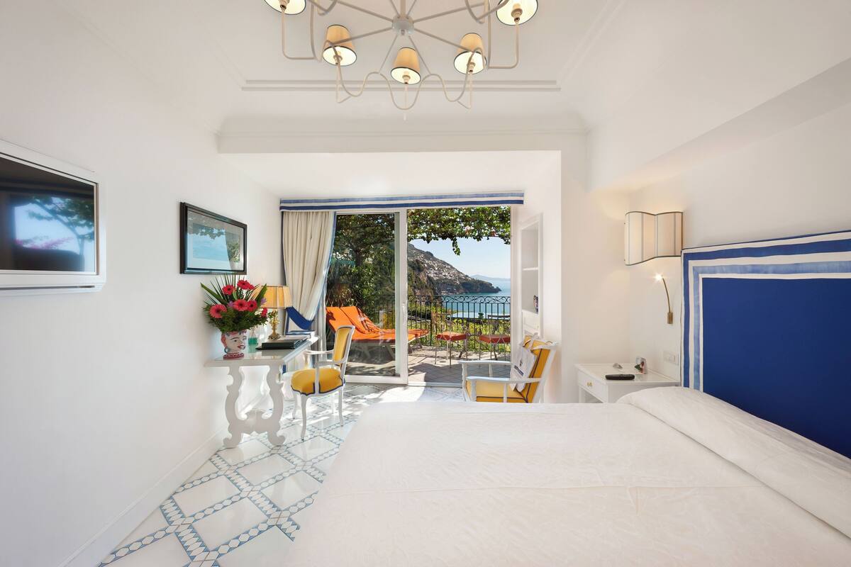 Habitación de hotel con cama, escritorio, silla, ventana y vistas al exterior.