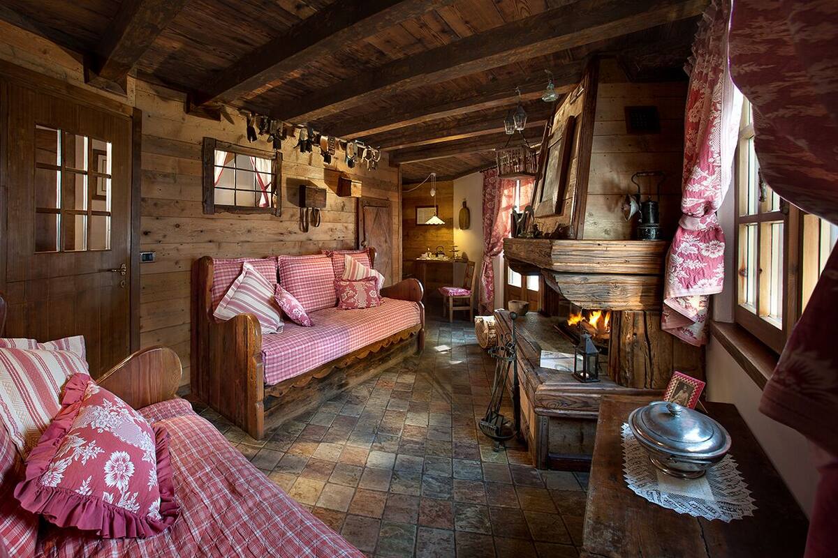 A cozy cabin interior with a wooden bench, a sofa, and a table with a lantern.