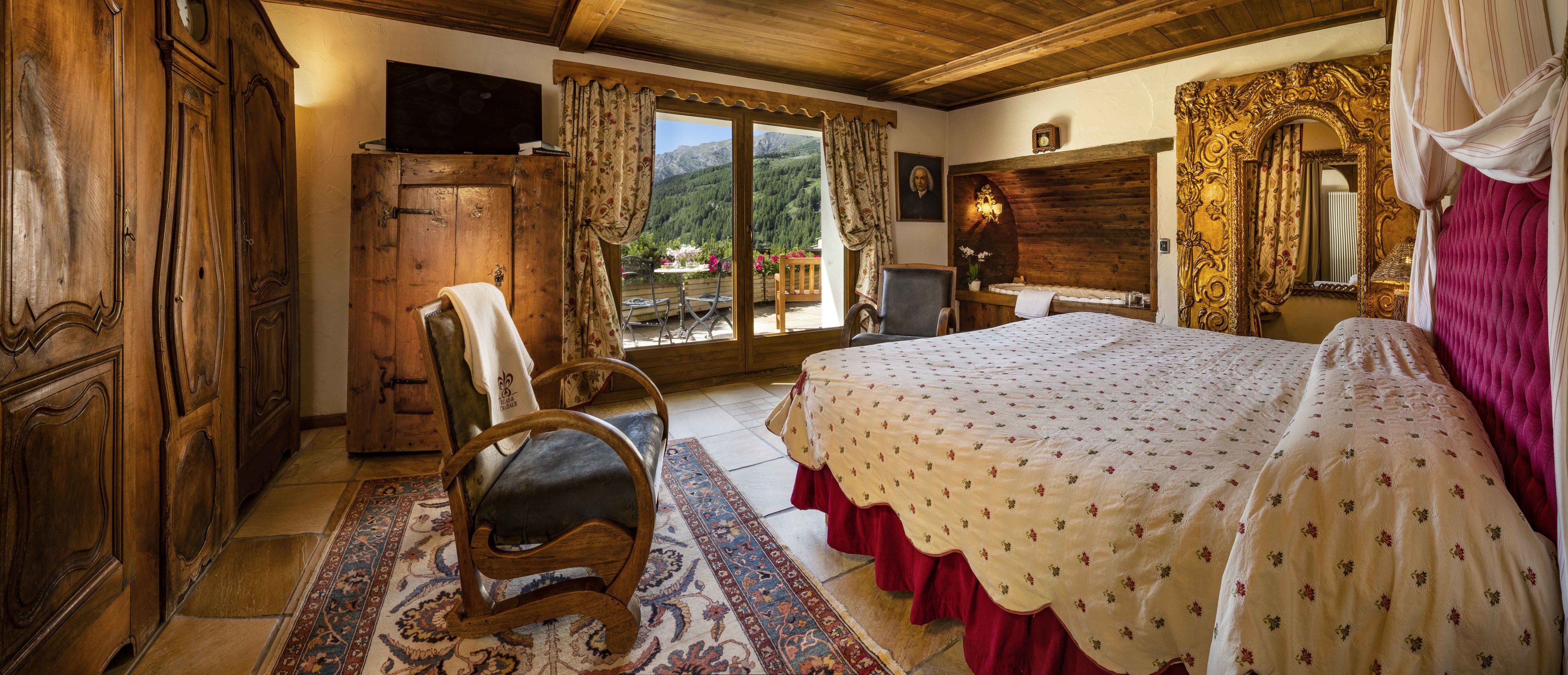 Une chambre traditionnelle avec un lit, des meubles en bois, une télévision et une vue sur les montagnes.