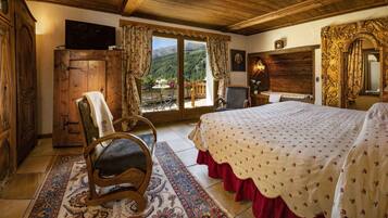Une chambre traditionnelle avec un lit, des meubles en bois, une télévision et une vue sur les montagnes.