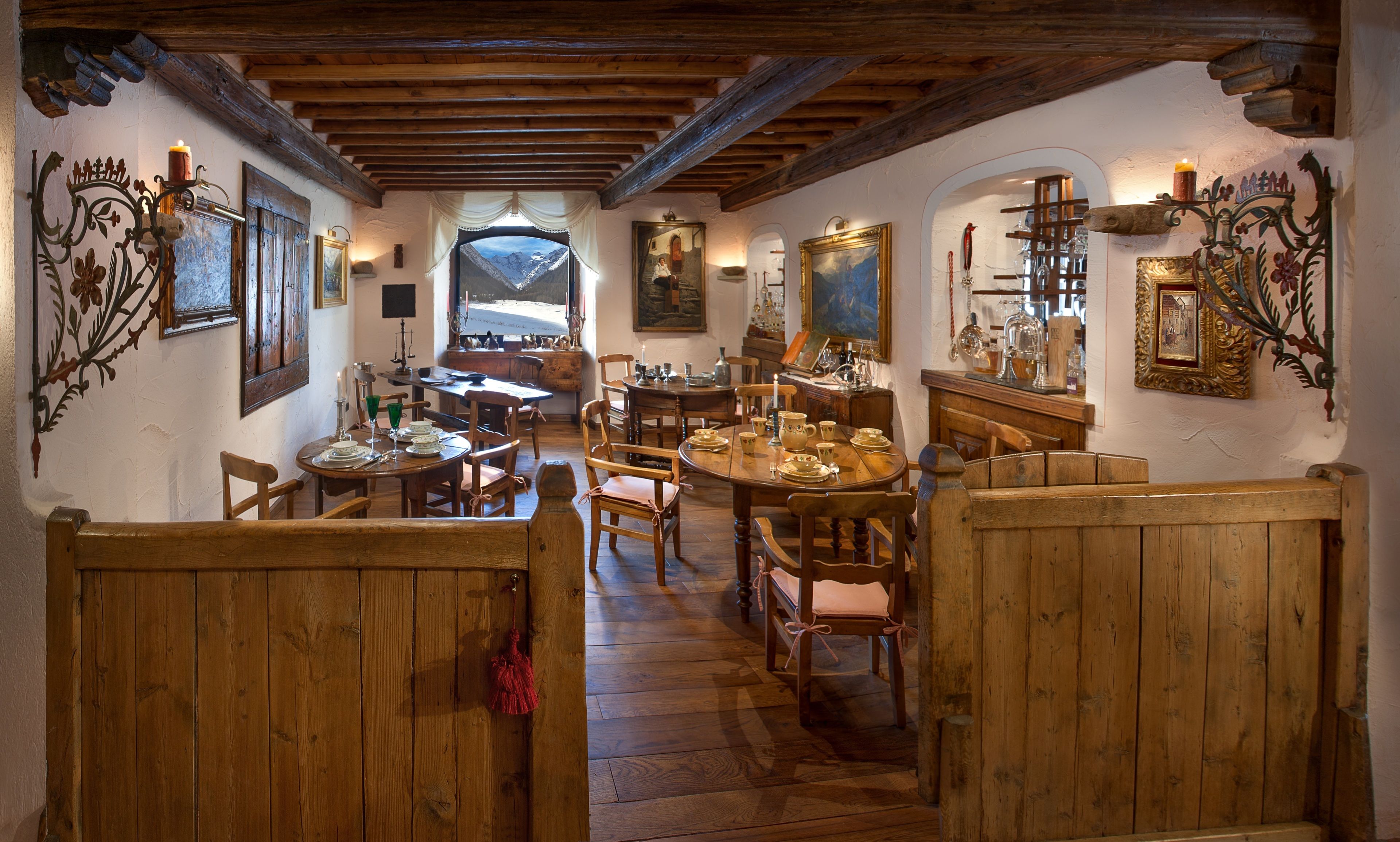A rustic dining area with wooden furniture and a view of mountains through a window.
