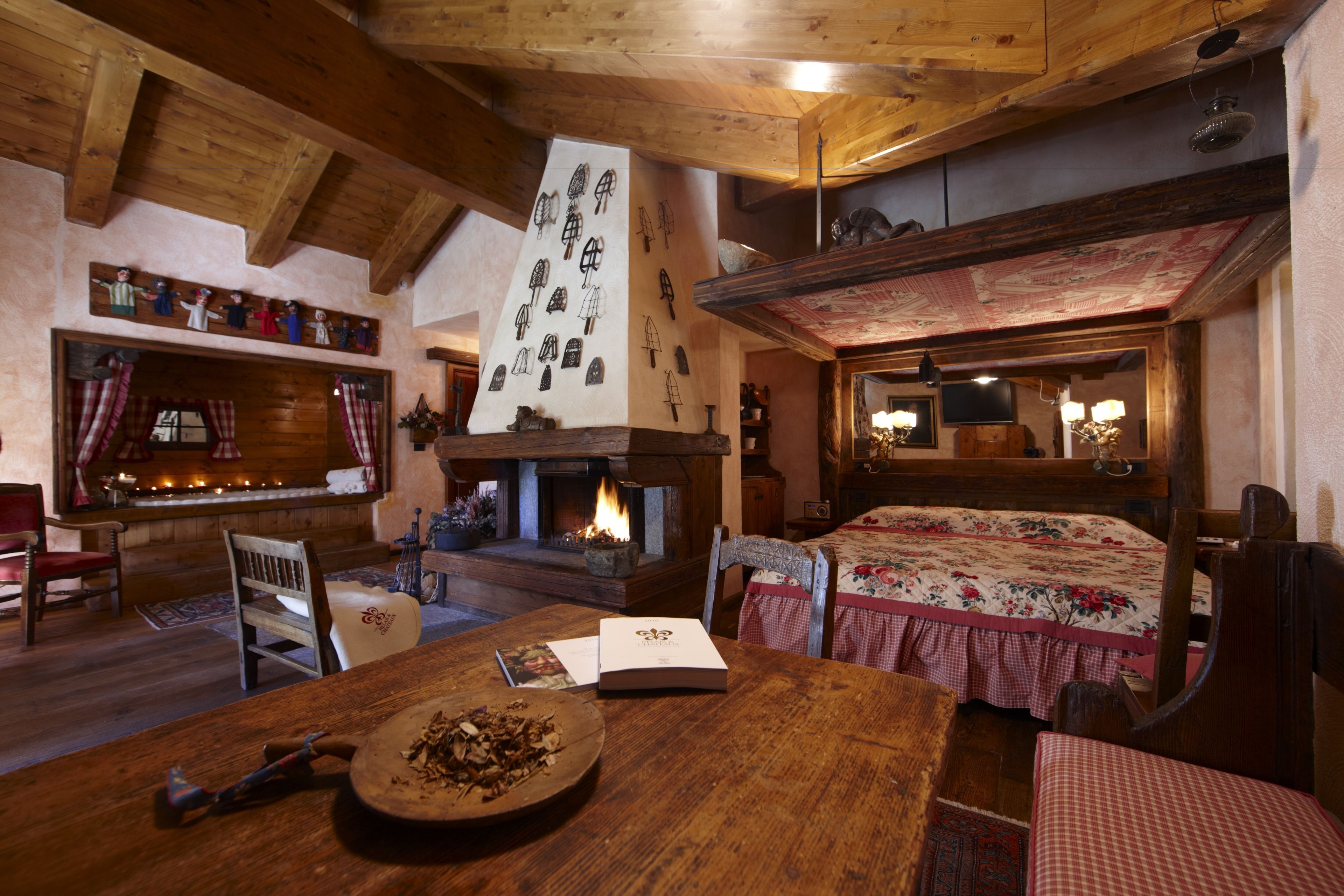 Ein gemütliches Zimmer mit Kamin, Holzmöbeln und einem Bett mit blumigem Bettbezug.