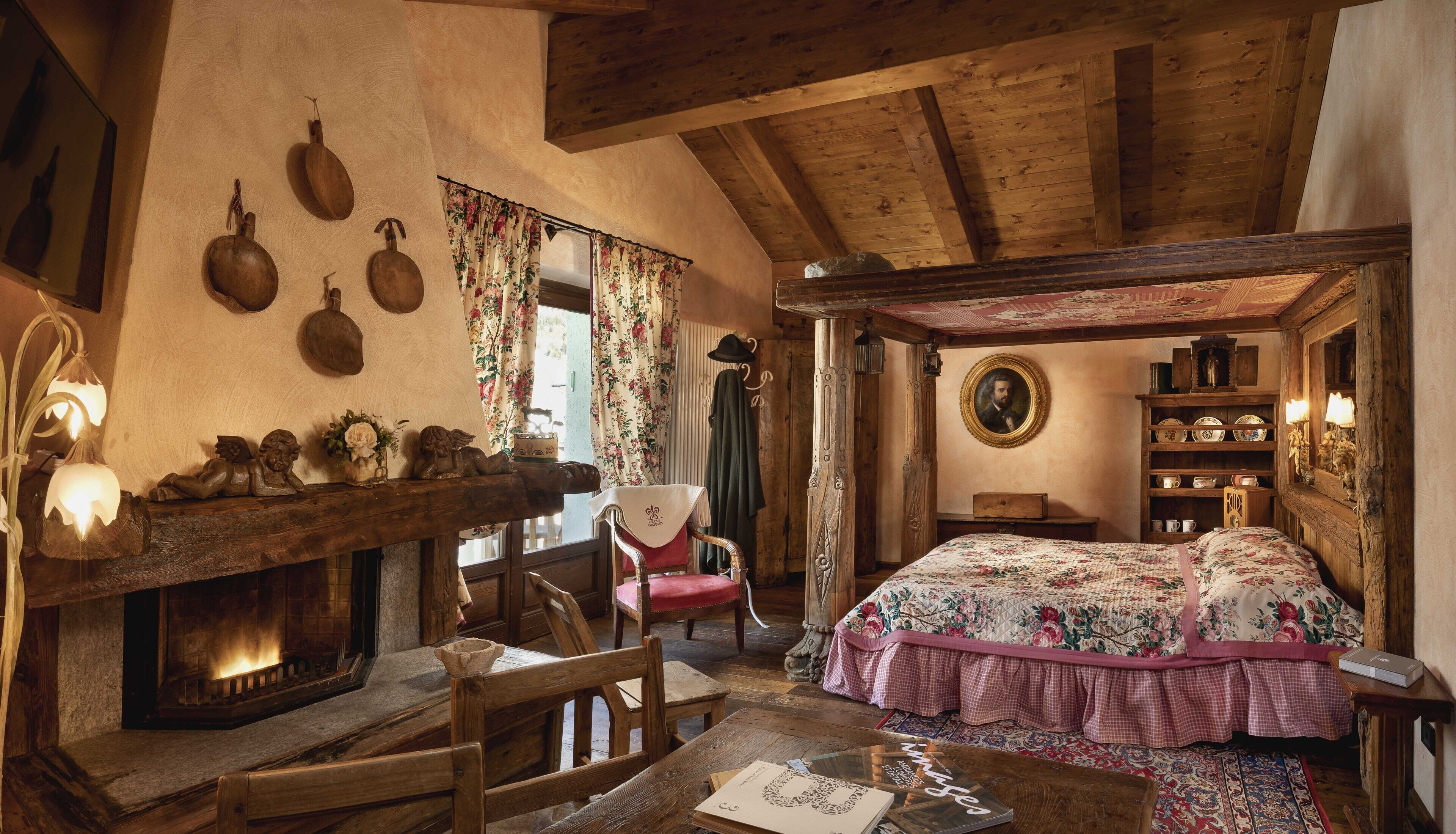 Una habitación rústica con techo de madera, chimenea, cama con ropa de cama floral y una silla de madera.