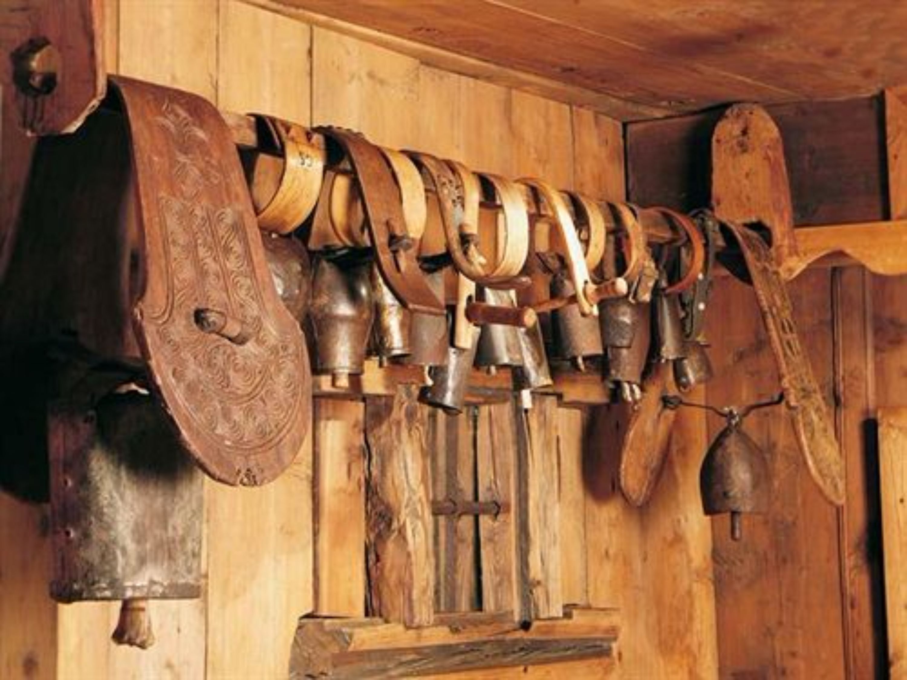 Un mur en bois orné d’une série de cloches, avec une grande cloche placée à gauche.