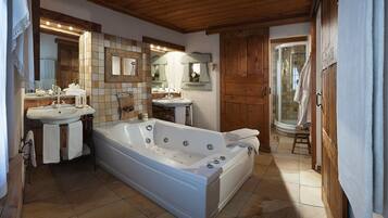 A bathroom with a large bathtub, two sinks, a mirror, and a shower area.