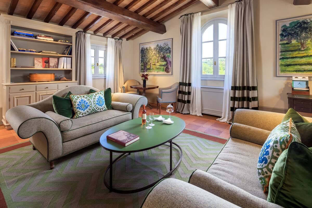 Un salon confortable avec un canapé, des fauteuils, une table basse et une bibliothèque.