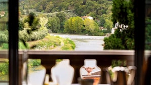 A view from a window overlooking a river, with a table in the foreground featuring a vase and a bowl. - Villa La Massa (Bagno a Ripoli)