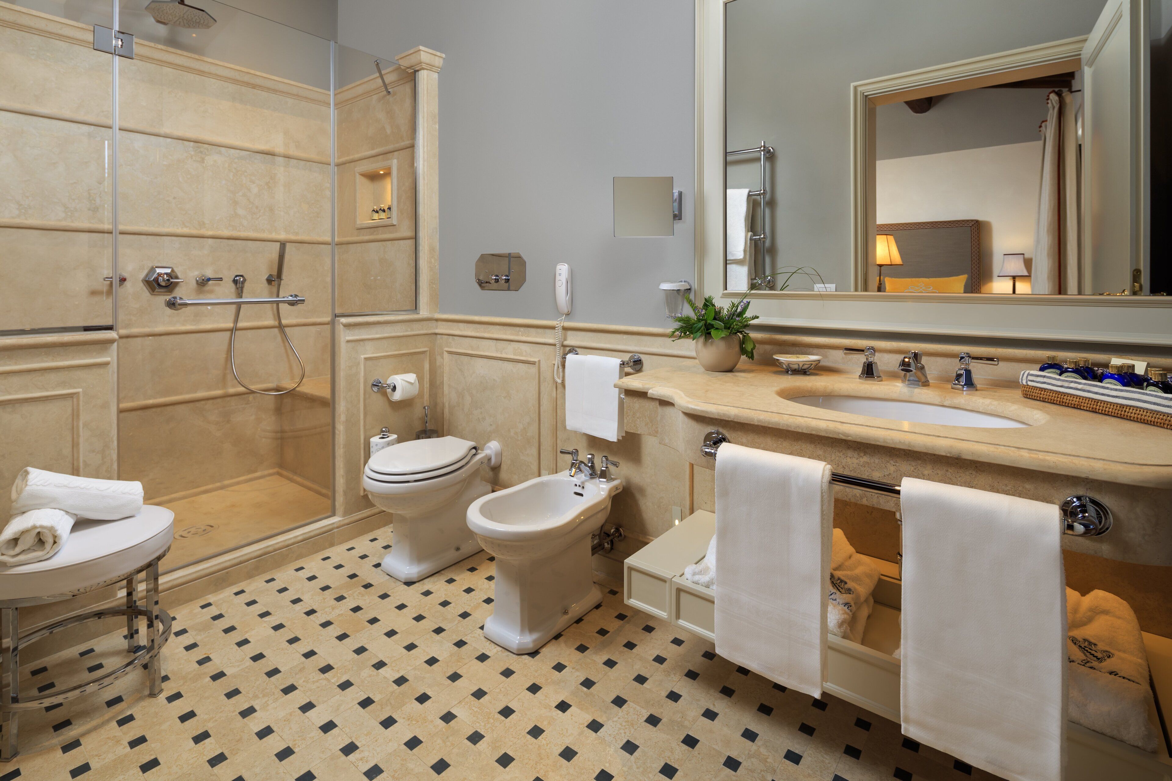 A bathroom with a shower, toilet, bidet, sink, and mirror.