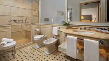 A bathroom with a shower, toilet, bidet, sink, and mirror.