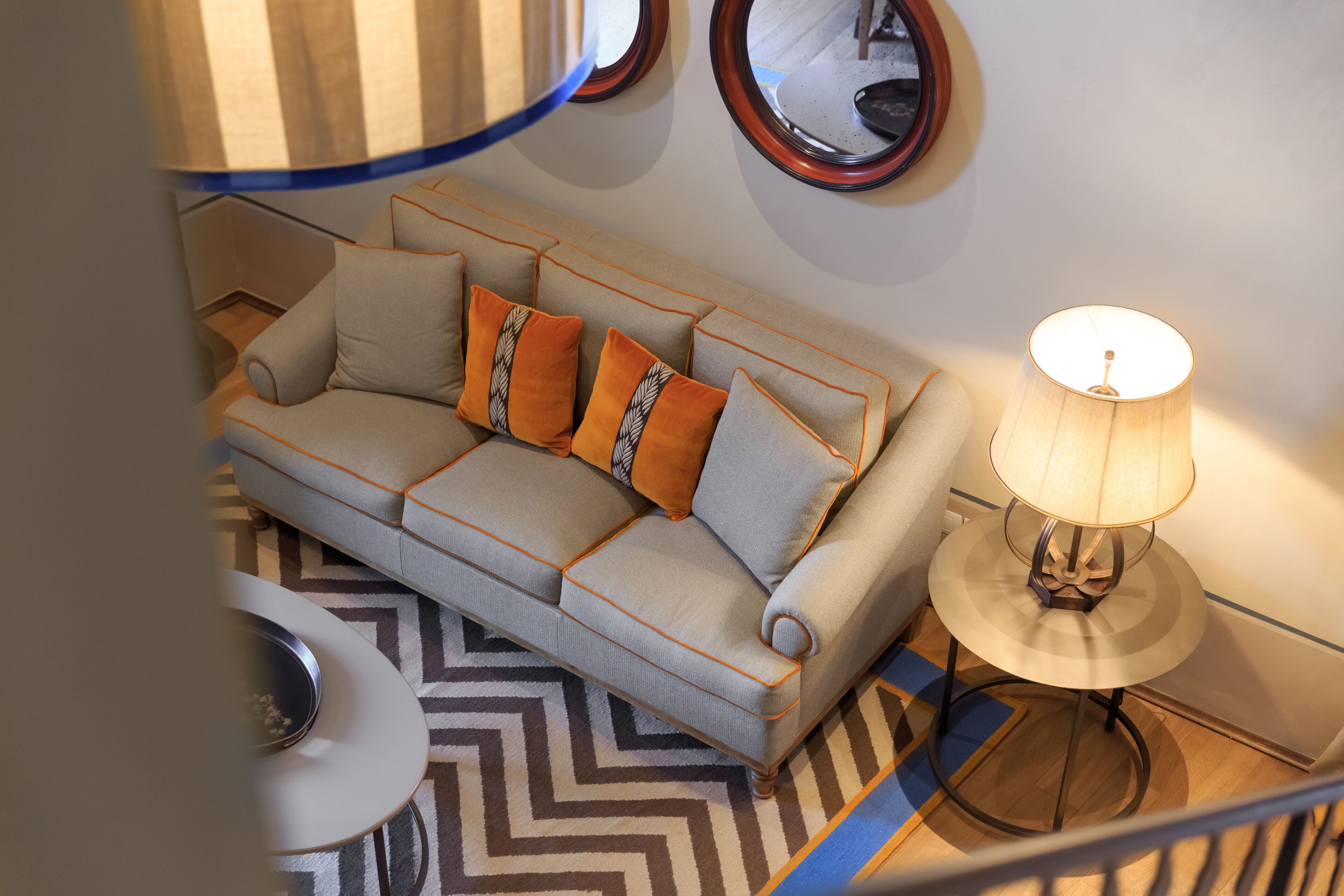 A living room with a sofa, a table with a lamp, and a patterned rug.