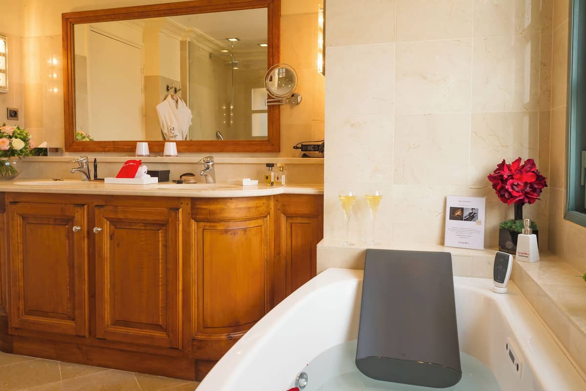 Une salle de bain avec un meuble-lavabo en bois, un grand miroir, une baignoire et une fenêtre.